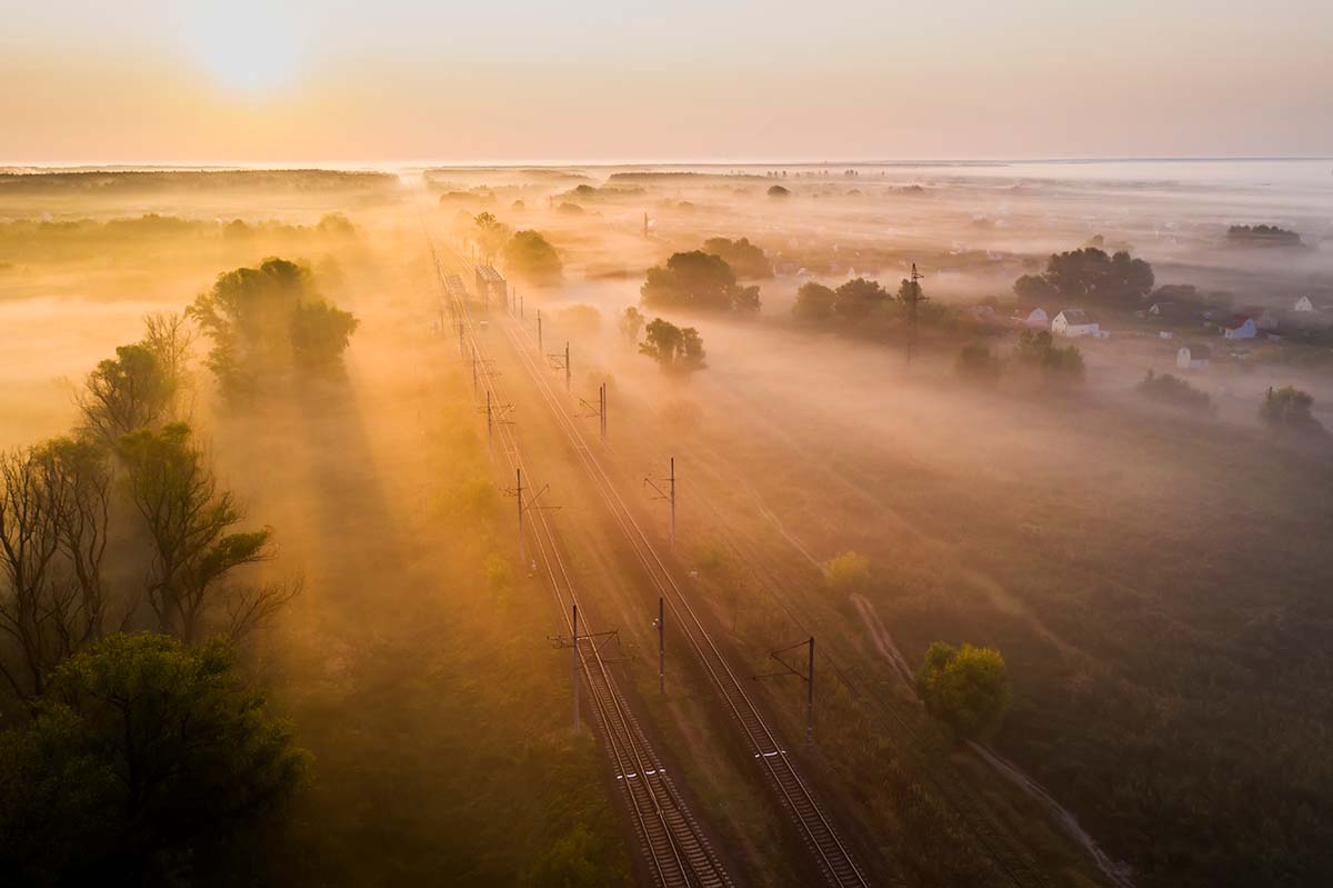 Train tracks running through landscape in morning fog
