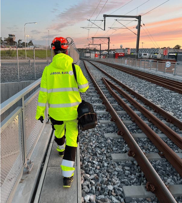 Man in Absol Rail work clothes walking on a train track